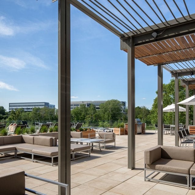 Fuse Cambridge Apartments - sundeck near pool surrounded by chaise lounge chairs, tables, and outdoor couches